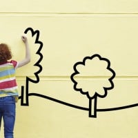 ילדה מציירת בית ועצים על קיר.