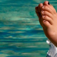 רגלי ילד על מזרן מתנפח בבריכה