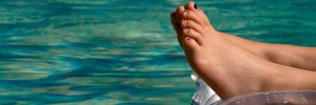 רגלי ילד על מזרן מתנפח בבריכה